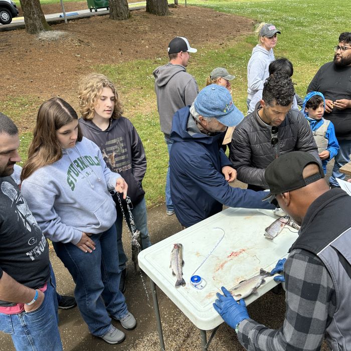 A group of youth stand by table as their fish catches are measured